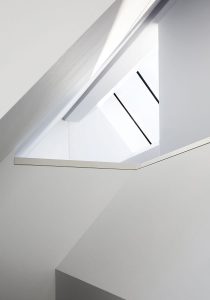 loft space with white painted angled walls and large roof light